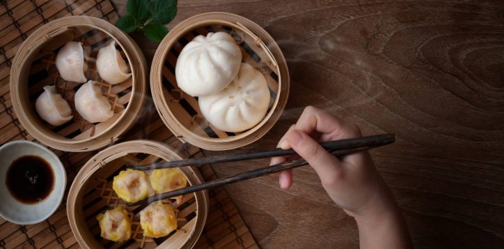 overhead-shot-woman-eating-chinese-steamed-dumpling-steamed-pork-bun-bamboo-steamer-2